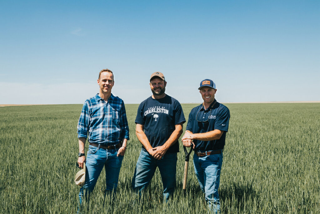 Carbon farming experts Jamie MacKinnon (left) from Anew and Travis Kraft from Locus AG (right) standing in a field with CarbonNOW farmer Scott Scheimer (middle)